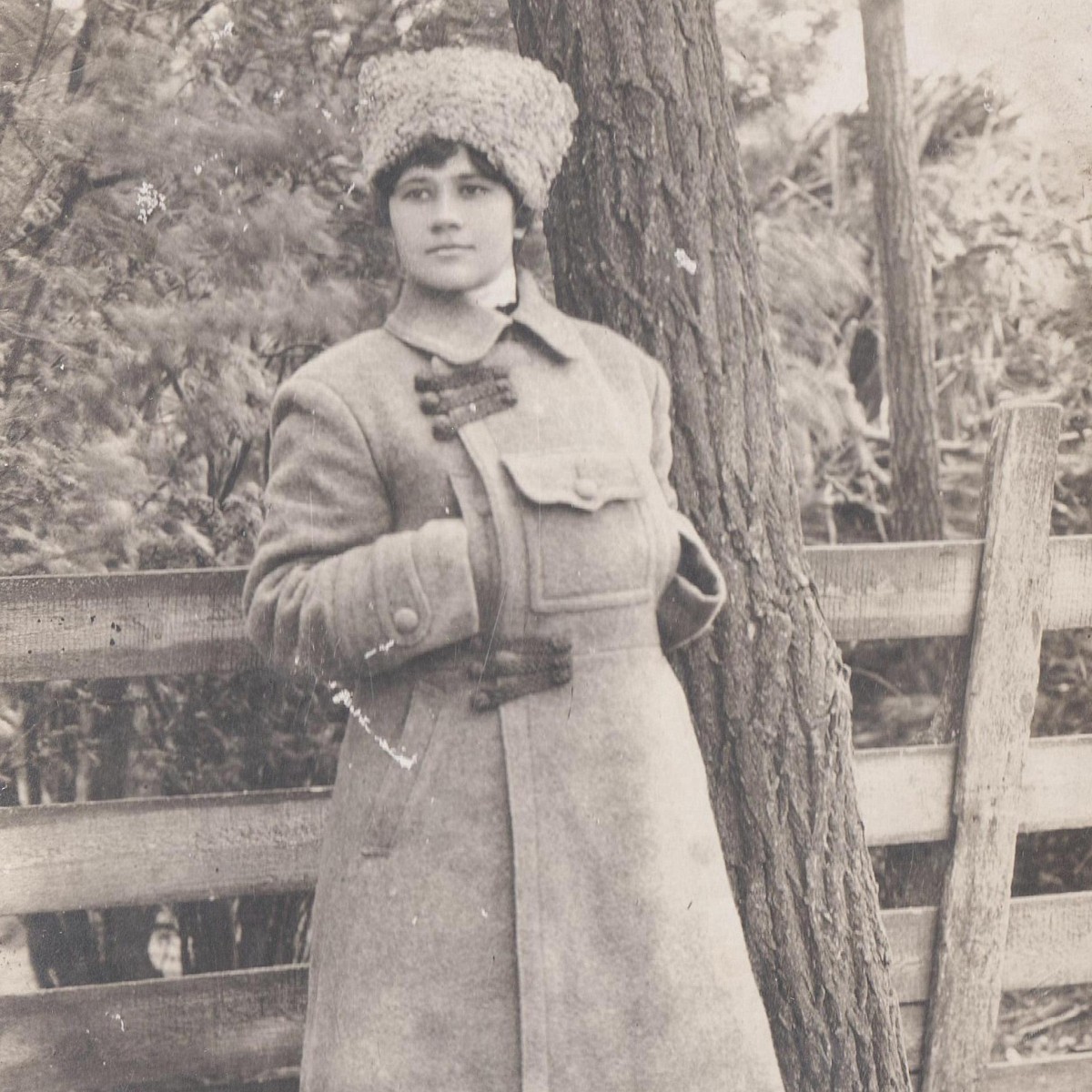 Photo of a girl in an army-style overcoat and papakha